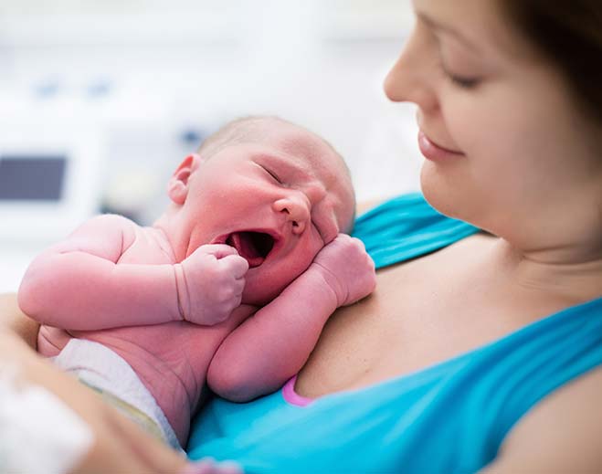 Newborn baby yawning while being held