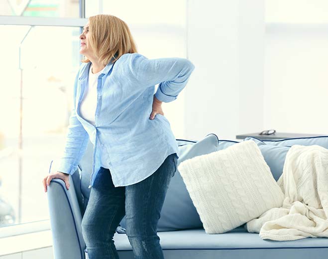 Person holding lower back in pain indoors